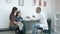 Male pediatrician examining throat of little girl sitting with her mother