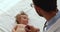Male pediatrician uses stethoscope listens baby heart beat