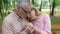 Male pensioner comforting sick elderly wife, sitting in hospital garden together