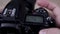 Male photographer adjusts settings on DSLR camera close up