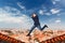 Male photographer jumping on the roofs of houses