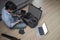 Male photographer sitting on wooden floor and putting camera accessories in special bag.