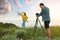 Male photographer taking picture of young woman with professional camera on hill