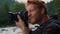 Male photographer taking pictures of nature. Redhead man using photo camera