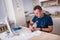 Male physician or nurse writing prescription while sitting on a white desk in a hospital lobby