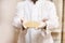 Male plastic surgeon holds breast implant and shows it to the camera standing on the background of wall in his cabinet