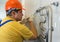 Male plumber repairing the battery in a helmet and with wrench