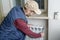 Male plumber repairing radiator with wrench.