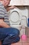 Male plumber sits in front of the toilet with the lid open