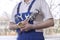 Male plumber in a white polo shirt and blue dungarees holds wrenches in his breast pocket. In his hands he holds tow and an adju