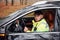 Male police officer in green uniform sitting in automobile and working with documents