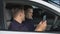 Male police officers chatting smartphones in car during work brake, rest