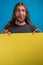 Male portrait making funny grimace while holding a yellow advertise banner