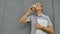 Male portrait of older coworker with silver laptop and cup of coffee waiting for a meeting near dark grey wall in the