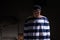 Male prisoner with an angry look standing near his bed in a small dark prison cell