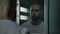 Male prisoner stands and looks at himself in the mirror in prison cell