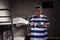 A male prisoner wearing prison uniform holding aluminum dishes i