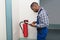 Male Professional Checking A Fire Extinguisher