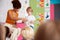 Male Pupil In Elementary School Classroom Reading Book To Class With Teacher