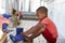 Male Pupil At Montessori School Putting On Wellington Boots