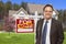 Male Real Estate Agent in Front of Sold Sign and House