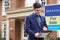 Male Realtor Standing Making Notes Outside Residential Property With For Sale Sign