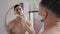 Male reflection in mirror in bath Arabian handsome Indian bearded man Hispanic guy applies white foam shaving gel male