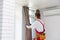 A male repairman installs a curtain rod and hangs curtains in the house. services to help with household chores and