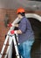 Male repairman standing on stepladder and repairing outdoor lamp