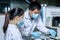 The male researcher prepares a column chromatography cartridge of the LC-MS instrument to analyze and train a female scientist to