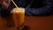 Male in restaurant stirs Thai Ice Tea with a plastic straw