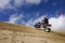 Male riding ATV up sand dune hill