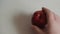 Male right hand picks up a red apple from the table with water droplets. Vegan choose fruit for lunch. View from above. Flat lay.