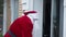 Male robber in Father Christmas costume opening door entering empty house. Caucasian man in Santa Clause outfit robbing