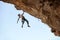 Male rock climber hanging with one hand