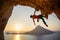 Male rock climber hanging with one hand on challenging route on cliff