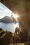 Male rock climber starting challenging route on cliff at sunset, female climber belaying him