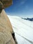 Male rock climbing a steep vertical granite rock climbing route in the French Alps near Mont Blanc above white snow glacier