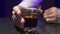 Male`s hand puts glass of alcohol liquid with ice on surface of black table