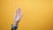 A male`s hand waves her hand in a gesture of farewell. Yellow background. The concept of gestures