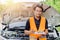 Male in safety uniform standing with check list at car open front hood. claim adjuster engineer mechanic man portrait happy