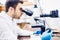 Male scientist, chemist working with microscope in pharmaceutical laboratory, examinating samples