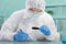 Male Scientist in PPE Suit working in Lab while Using Magnifying glass Checking Sample in Sampling Plate.