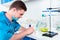 Male scientist in uniform wearing a mask preparing powder on ceramic plate for some research in a laboratory