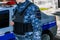 A male security guard in full gear is standing next to a company car.