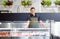 Male seller showing seafood at fish shop fridge