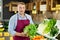 Male seller in uniform working in grocery shop, posing with salad