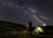 Male shows female up on evening starry sky at Milky way against the backdrop of mountains