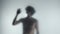 Male silhouette behind a transparent frosted curtain or glass close up. A man is guiding her hand on the surface of the