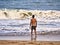 Male silhouette goes in the sea water on a sand beach. Young adult boy on the beach - beautiful background with copy space